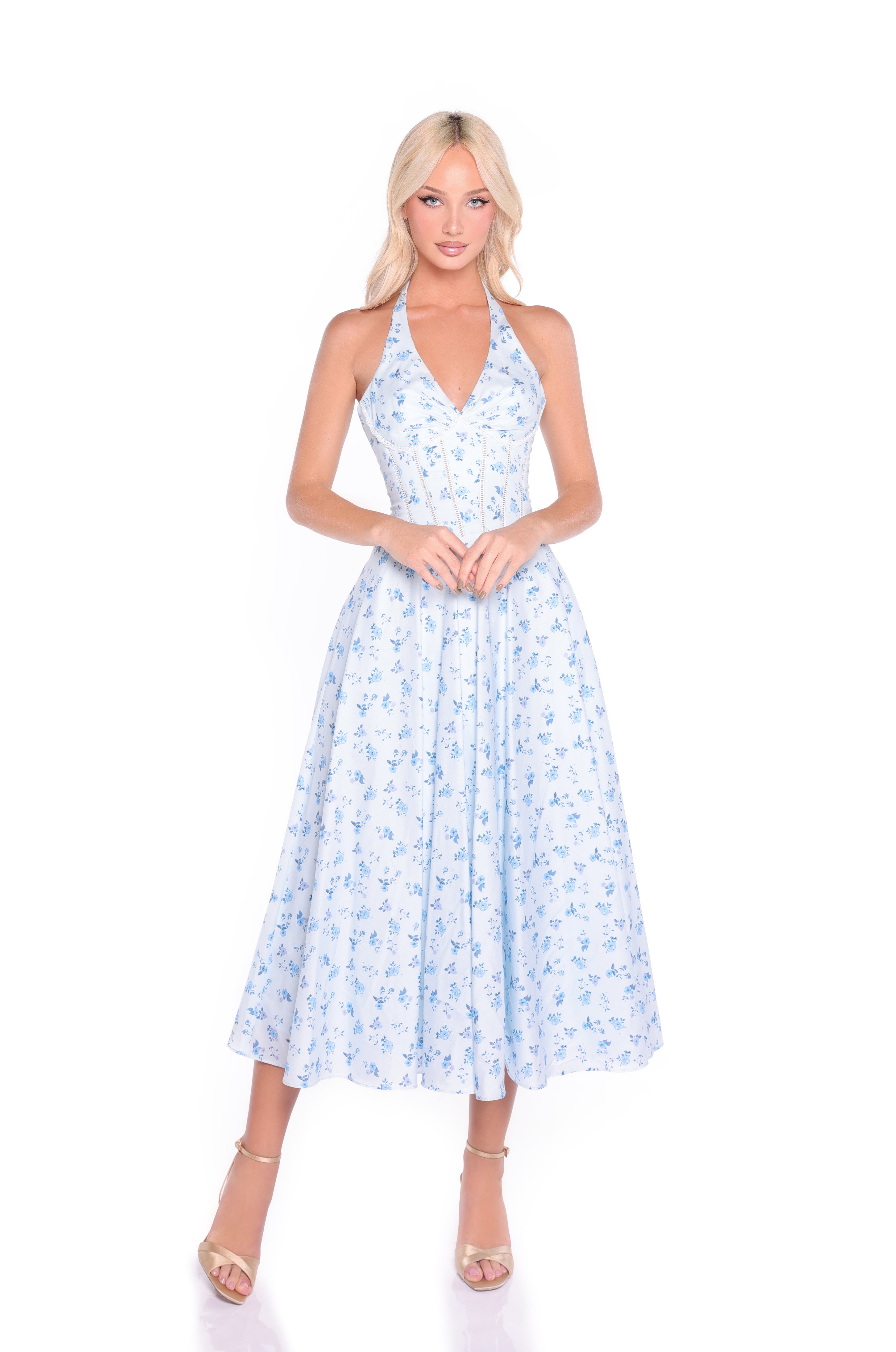 A woman models the Eliza Light Blue Floral Halter Summer Midi Dress, featuring a corset bodice and flared skirt, paired with nude high-heeled sandals, against a white background.
